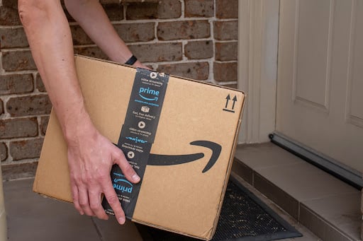 An Amazon parcel being brought by an Amazon delivery service to someone’s doorstep.