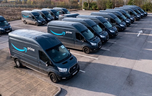 A row of Amazon Prime delivery vans parked at a parking lot