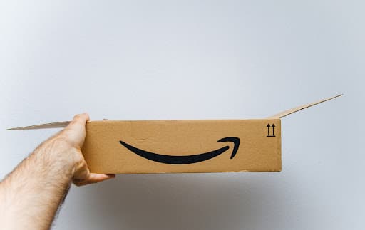 An Amazon cardboard box held by a man’s hand.