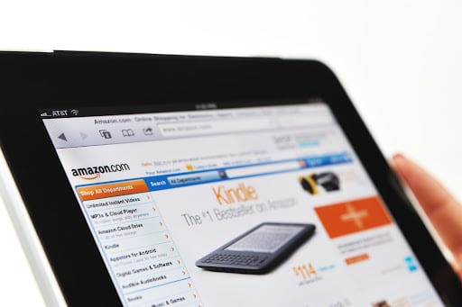 Woman holding a tablet displaying the Amazon website.