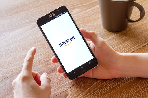 Image Alt-Text: Hand holding screenshot of Amazon application showing on mobile phone.