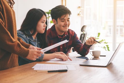 Two young Amazon sellers are creating well-outlined strategies and action plans on their computers to attract more online sales and customers.