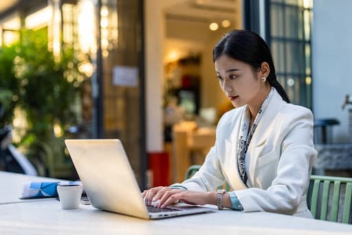 An Asian-American businesswoman working in front of her laptop at a cafe.